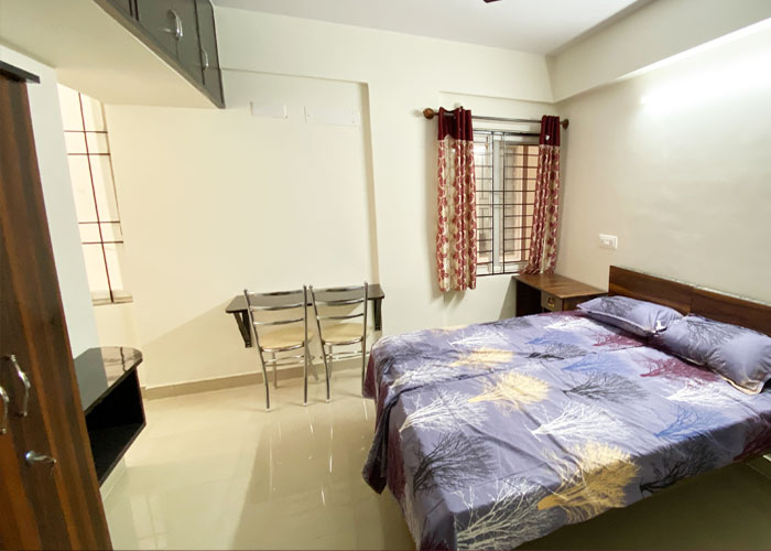 Furnished bedroom with bed and study table at S V Moon Homes in Munnekollal
